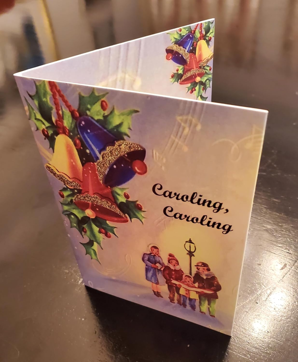 Christmas card with carolers and ornaments on a reflective surface