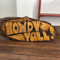 Wooden sign with 'HOWDY Y'ALL' text on a wooden surface