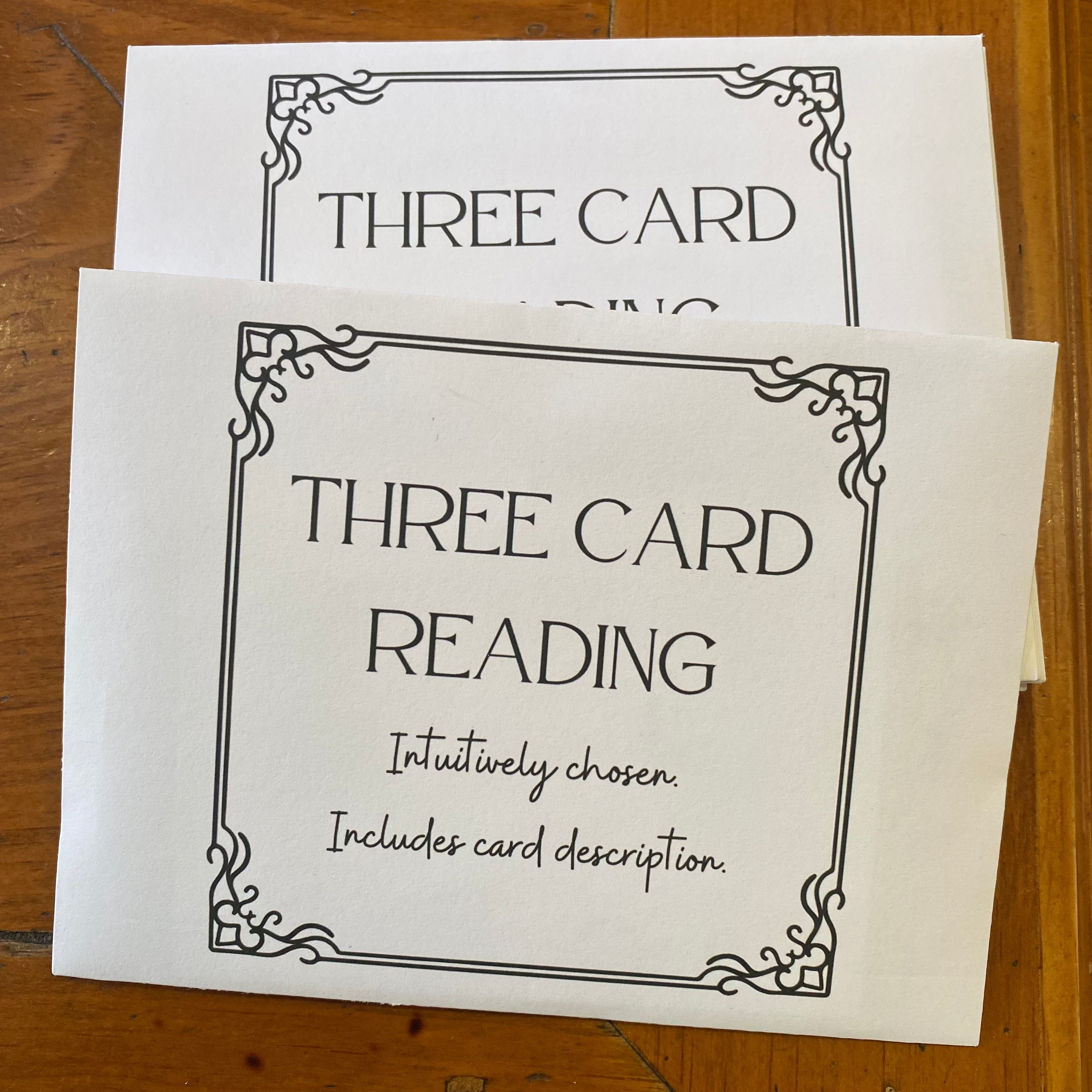 Two cards with 'Three Card Reading' text on a wooden surface