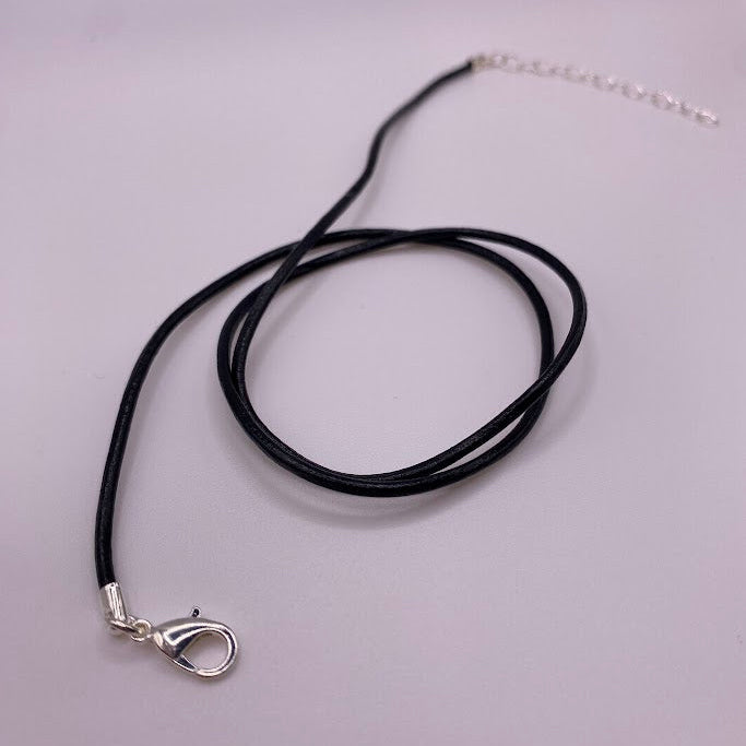 Black cord necklace with silver clasp on a light gray background