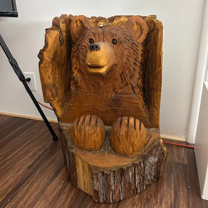 Wooden bear sculpture on a log base indoors