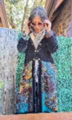 Person wearing a colorful coat with a patterned scarf, standing against a textured wall.