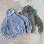Two hoodies, one blue and one gray, on a textured surface.