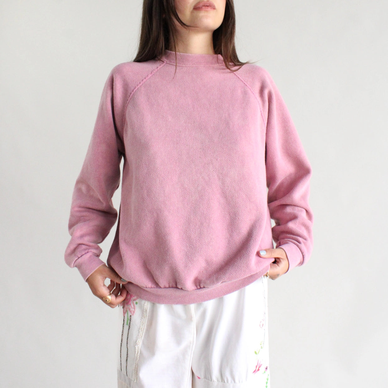 Person wearing a pink sweatshirt against a plain background