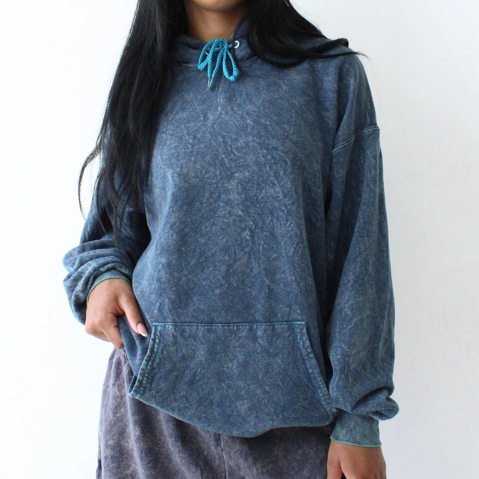 Person wearing a blue hoodie and gray sweatpants against a white background