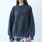 Person wearing a dark gray sweater and plaid pants against a white background