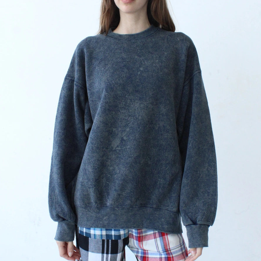 Person wearing a dark gray sweater and plaid pants against a white background