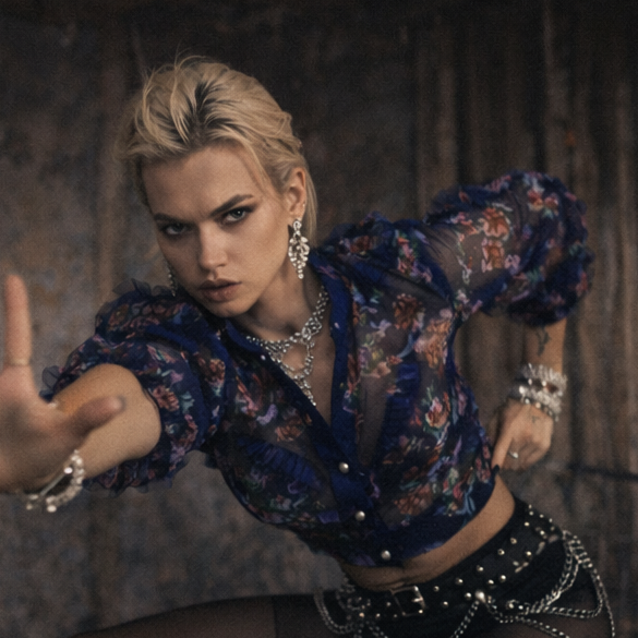 Woman in a stylized outfit posing dramatically against a dark background
