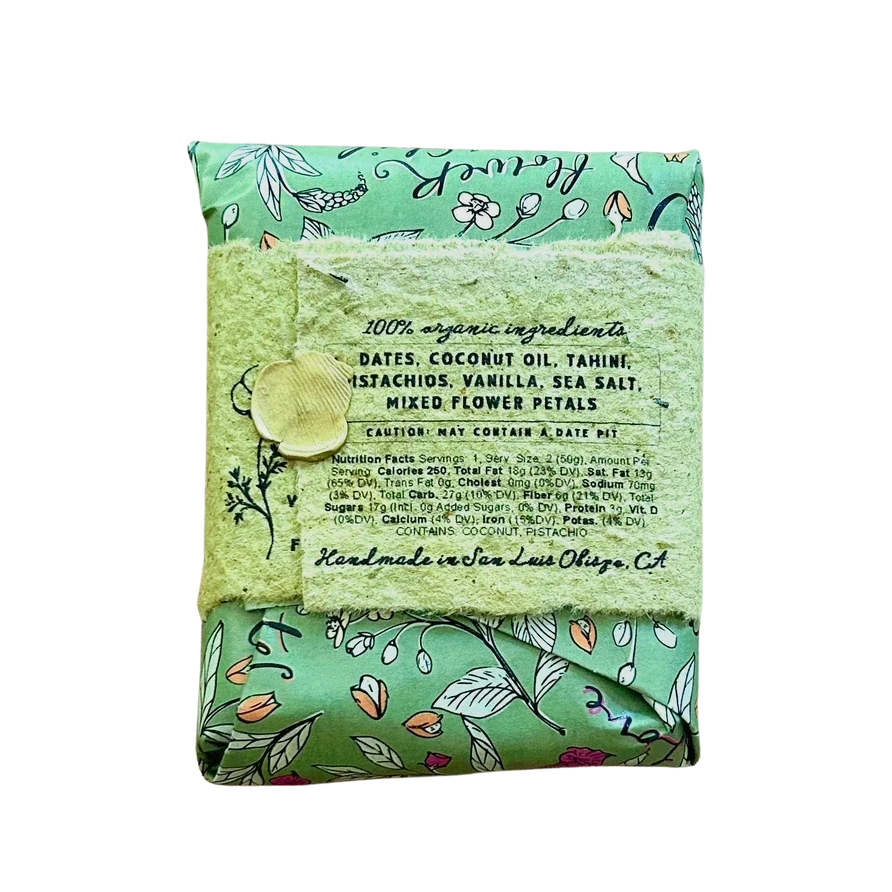 A folded bar of handmade soap in a mint green floral patterned wrapper, tied with a matching lace ribbon and a wooden bead, on a plain white background.