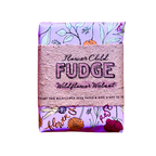 A packaged bar of Flower Child Fudge Wildflower Walnut fudge, wrapped in a textured pink paper band with floral illustrations on a light purple background.