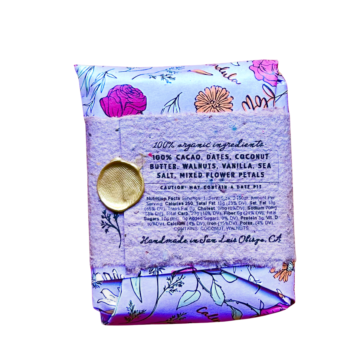 A packaged food product, specifically a folded pouch of coconut flax seed butter, featuring a light purple floral pattern with a gold wax seal on the front label.