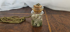 Handcrafted miniature glass vial pendant necklace filled with real preserved bone fragments, clear quartz crystal points, and green moss with an antique bronze chain.