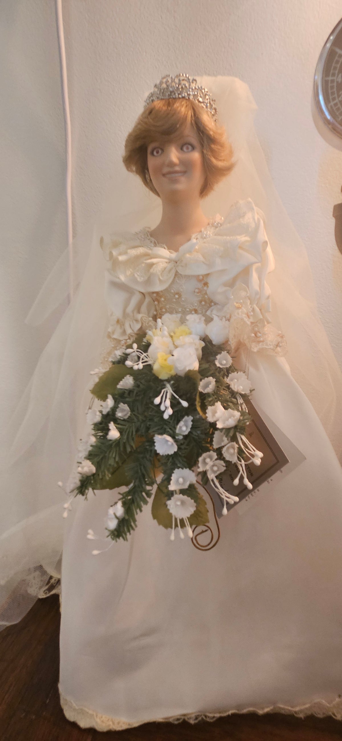 Vintage porcelain collector doll of Princess Diana in an ivory royal wedding gown with ruffled bodice, tiara, long veil, and cascading floral bouquet.
