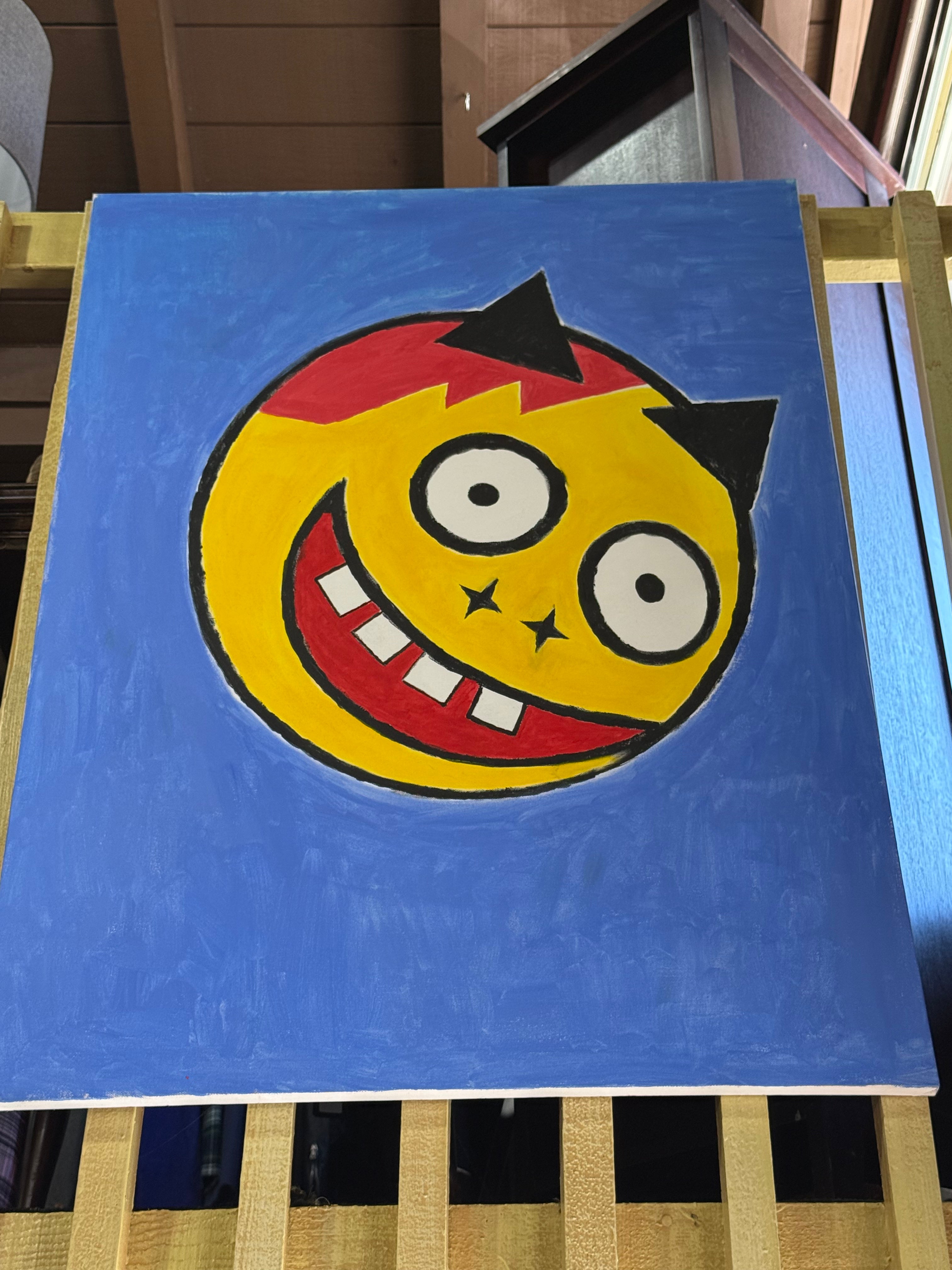 "Smile" by Shelf4Life original canvas painting featuring a large stylized yellow face with a patch of red hair, black devil horns, wide eyes, and a massive gap-toothed grin against a solid textured medium blue background.