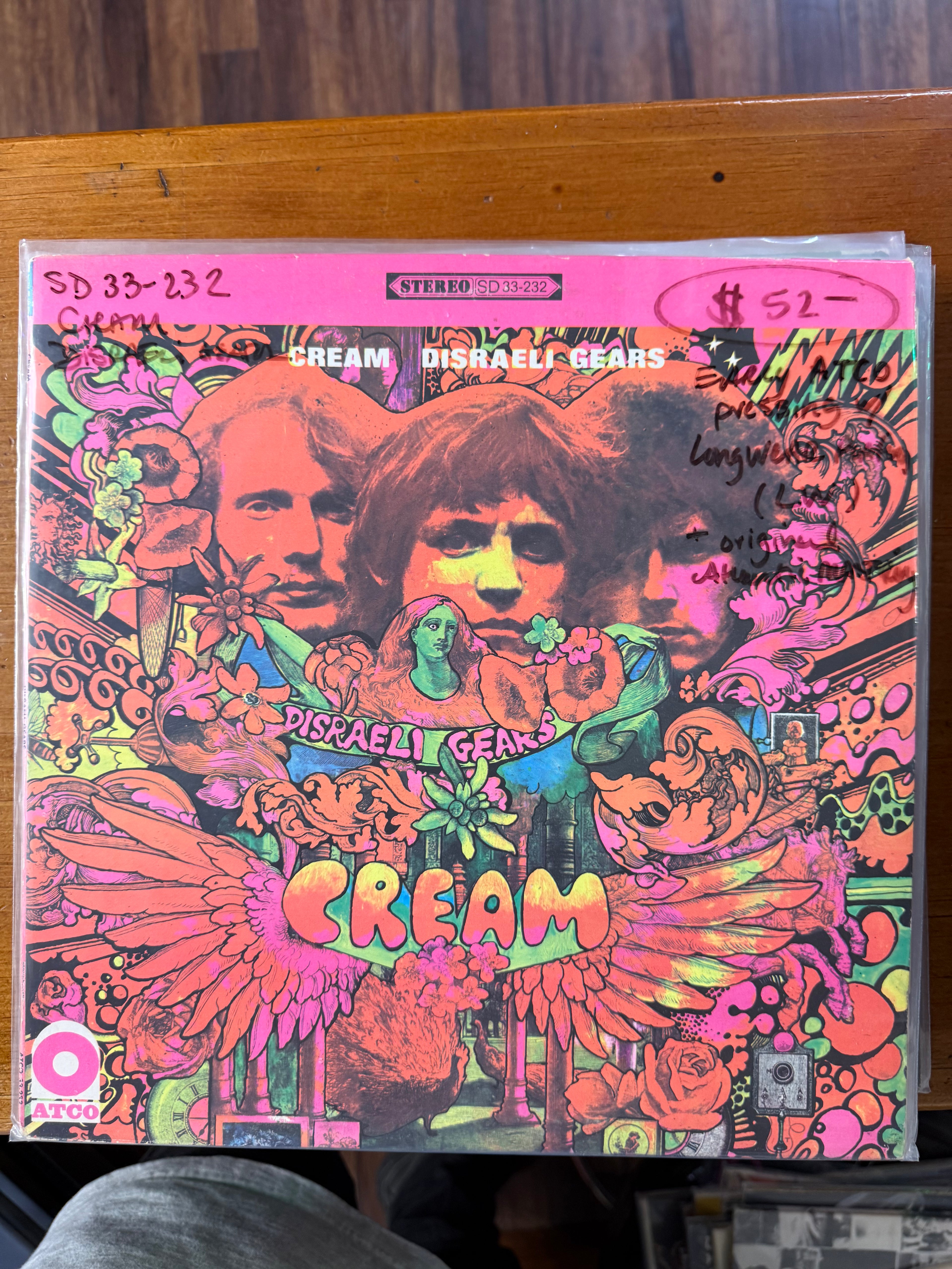 Front cover of Cream's 1967 vinyl album Disraeli Gears featuring vibrant pink, yellow, and orange psychedelic artwork by Martin Sharp with portraits of Eric Clapton, Jack Bruce, and Ginger Baker.