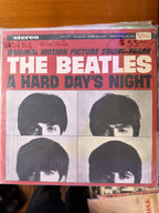 Front jacket cover of The Beatles A Hard Day's Night original motion picture soundtrack vinyl album on United Artists, featuring bold pink and gray title typography above four close-up black-and-white portraits of John, Paul, George, and Ringo.