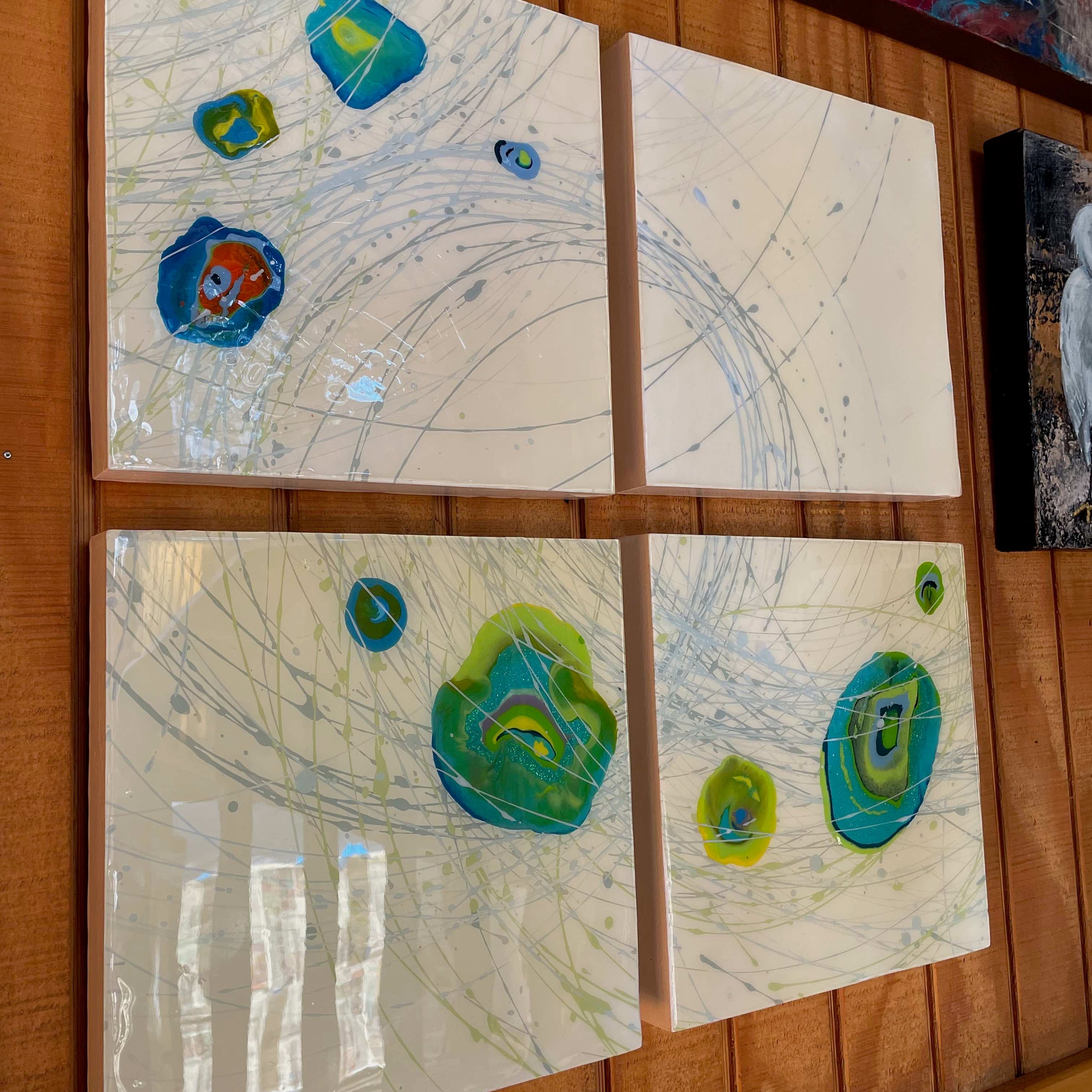 Four abstract artworks on a wooden surface