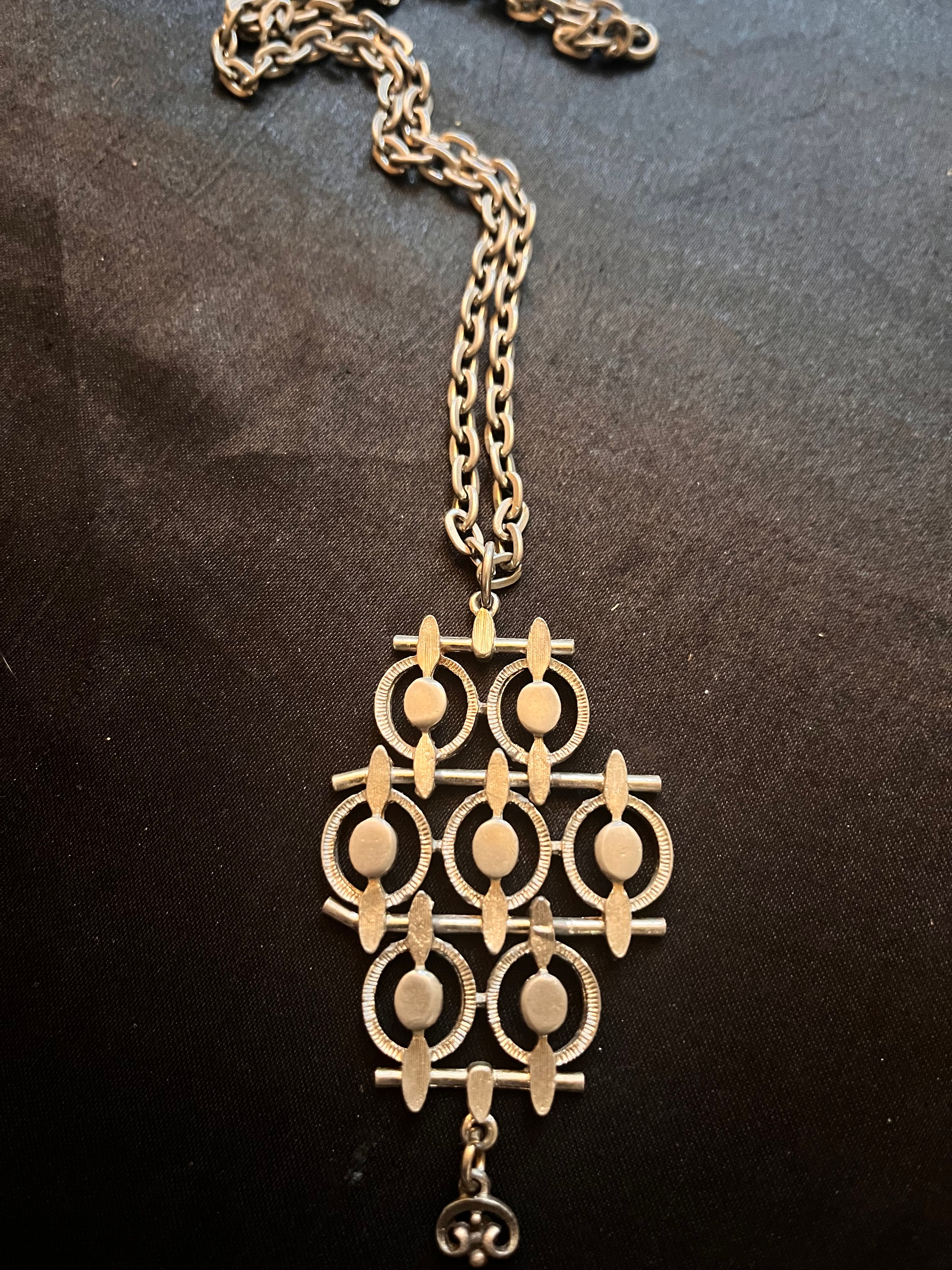 Shop our mid century brutalist silver tone necklace. This spectacular vintage modernist pendant features an abstract geometric lattice design and heavy link chain.