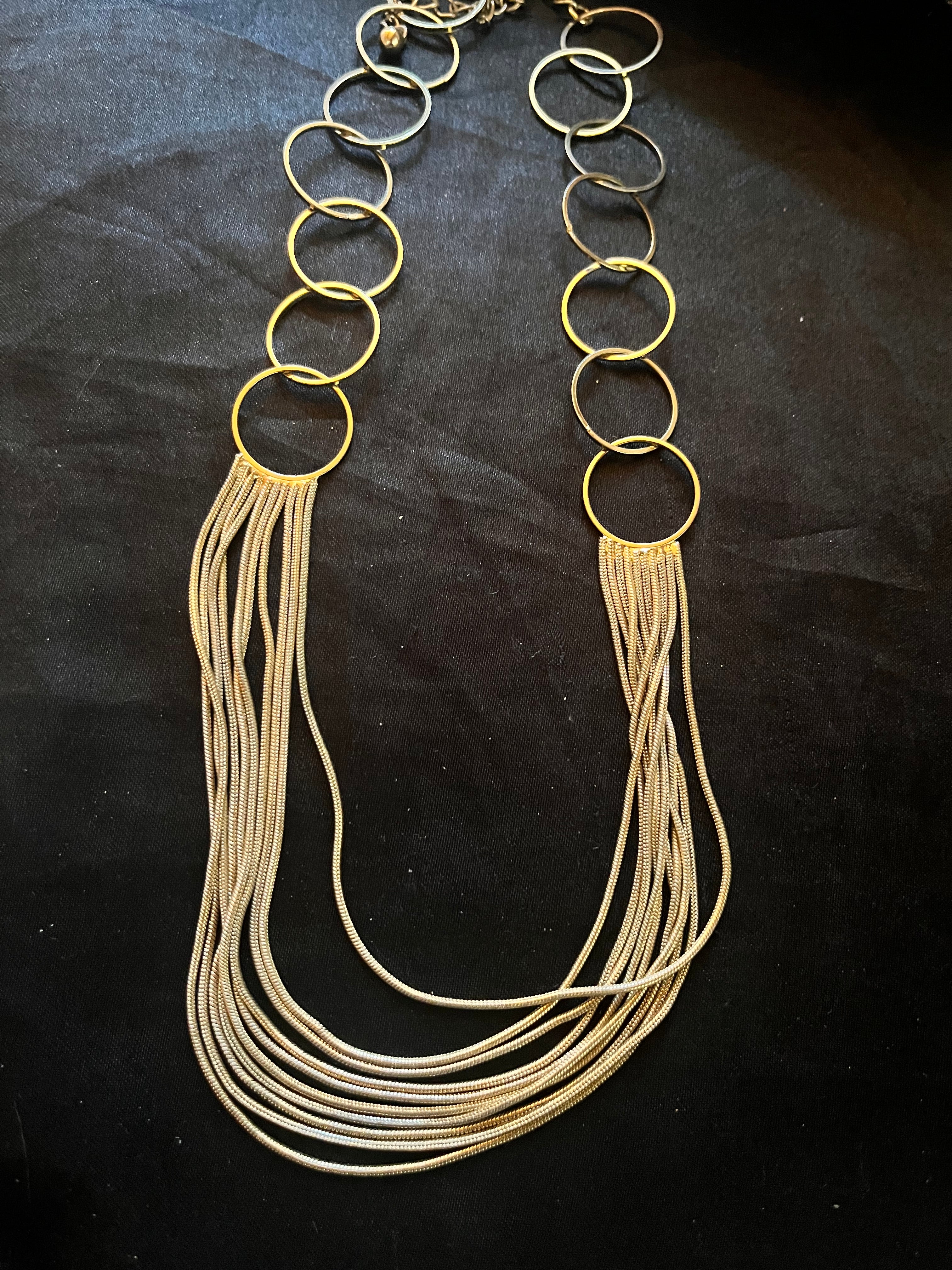 Shop our vintage multi strand gold tone necklace. This beautiful retro statement piece features a fluid liquid chain drape and bold open geometric circle links.