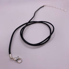 Black cord necklace with silver clasp on a light gray background