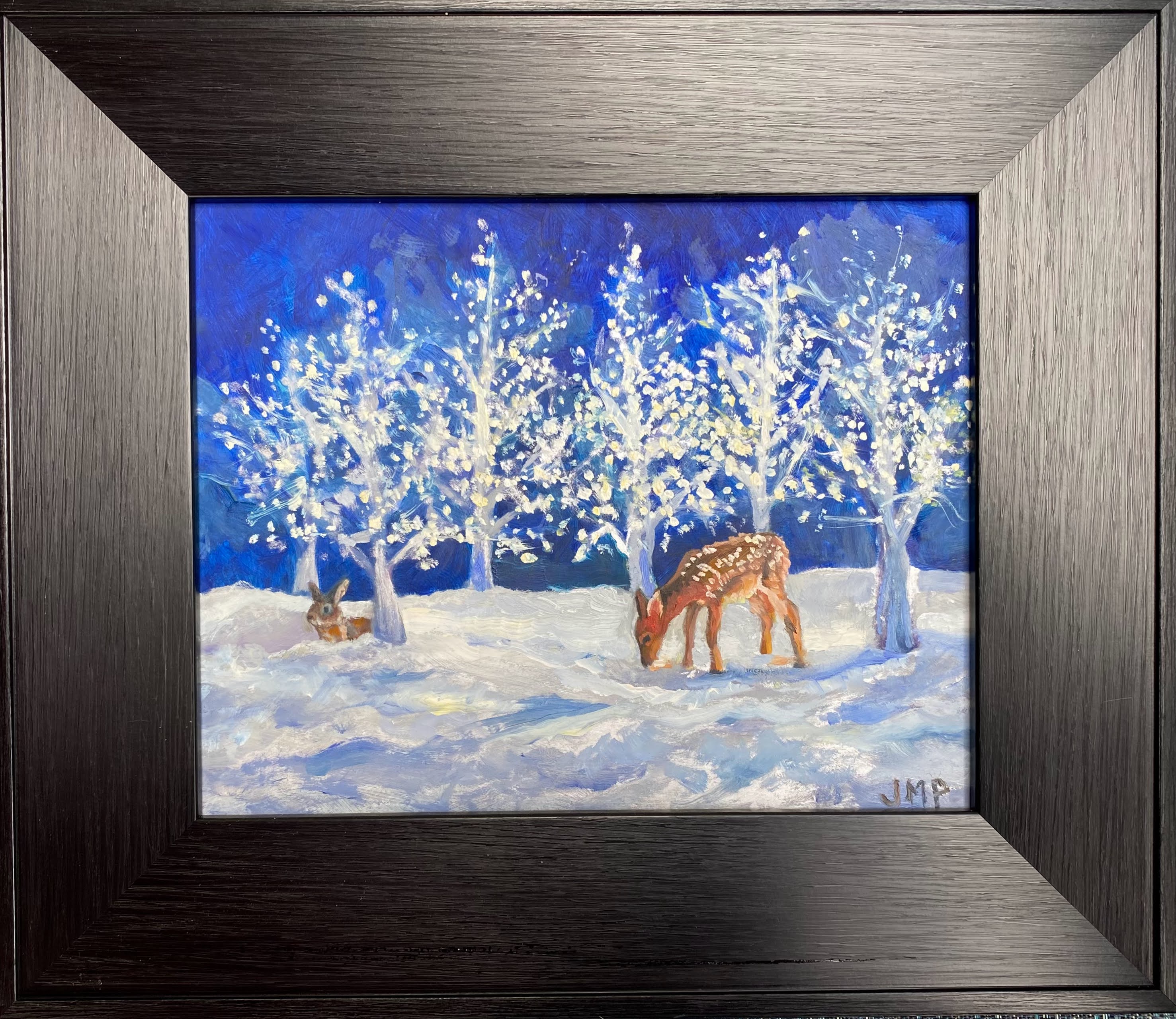 Framed artwork of deer in a snowy landscape with illuminated trees.