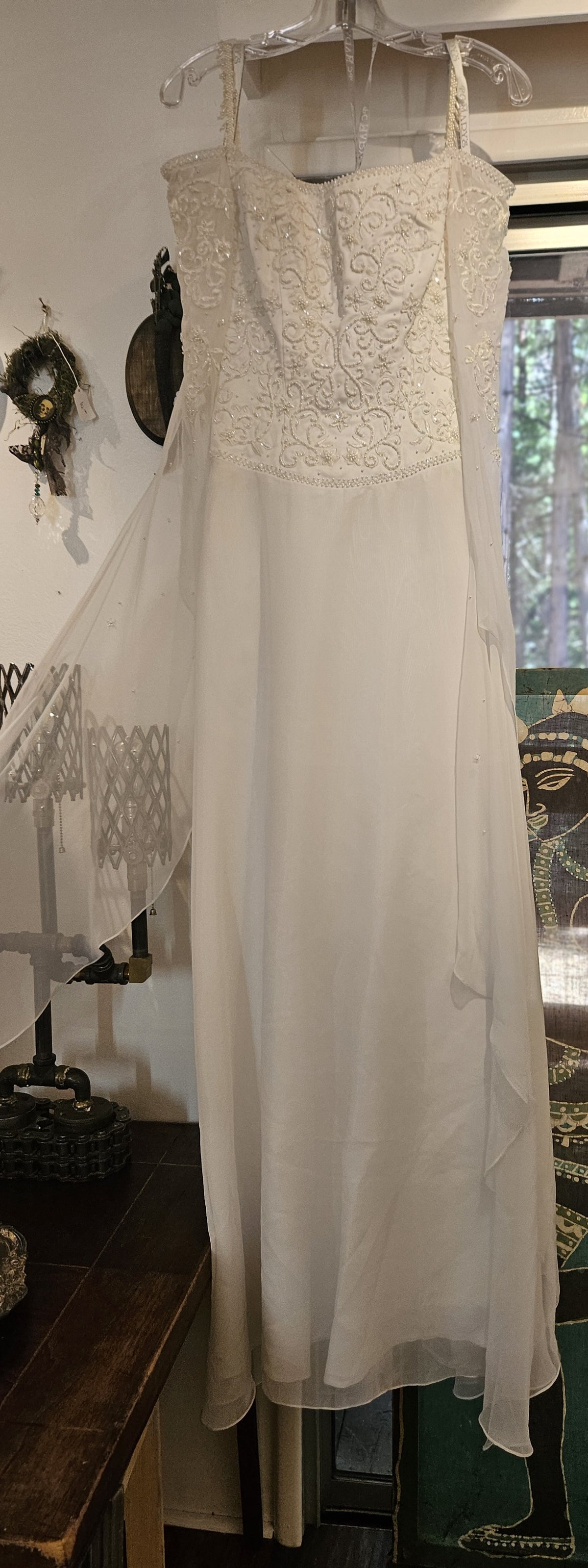 Vintage Mary’s Bridal style 2001 wedding gown in size 4 featuring an embroidered beaded bodice, delicate straps with flowing sheer chiffon shoulder drapes, and an A-line skirt on a hanger.